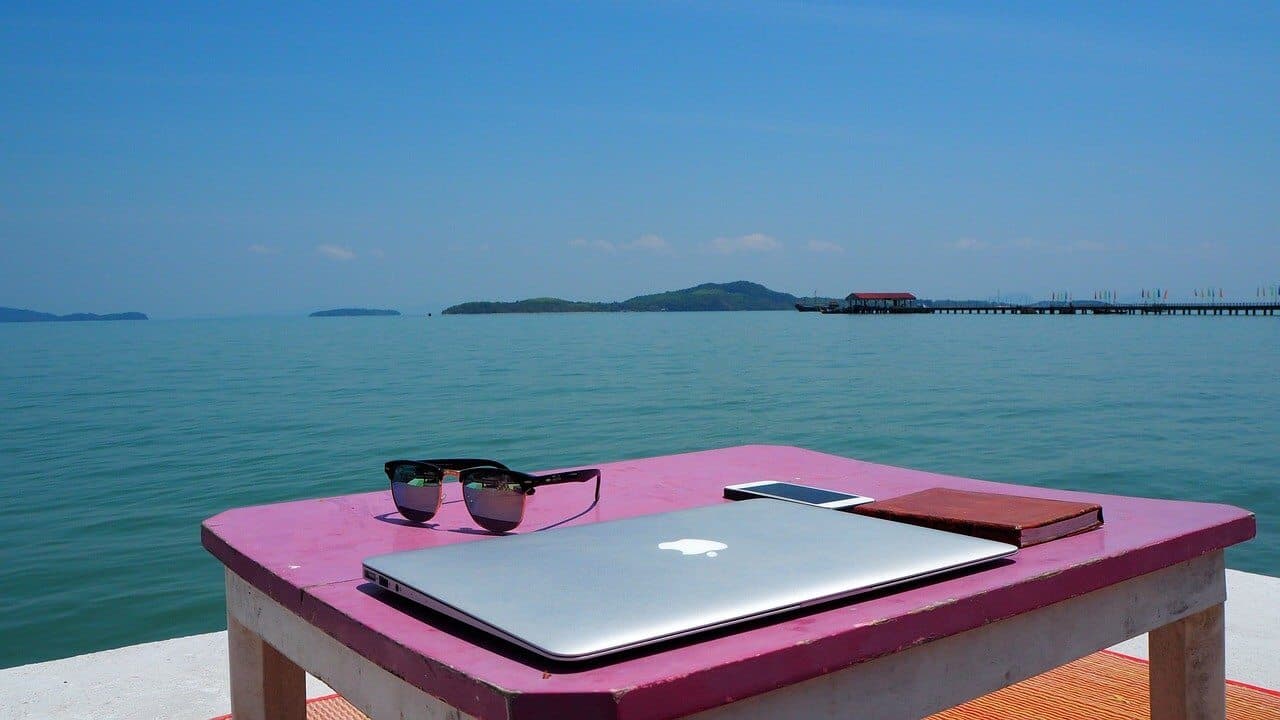 Closed MacBook in the foreground, beach in Thailand in the background